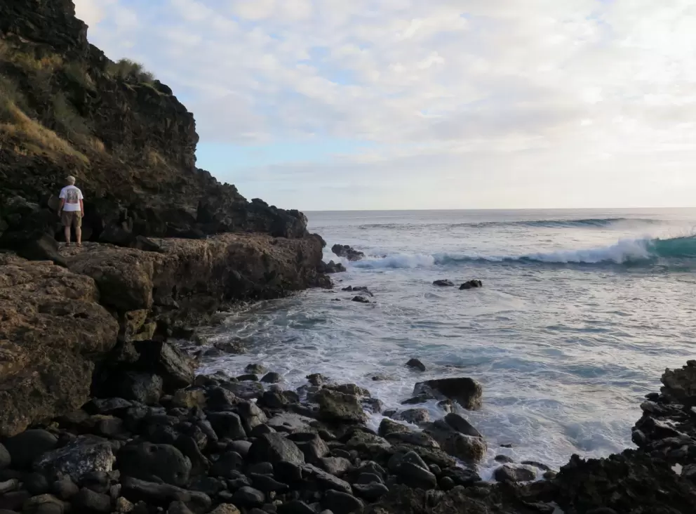 A man walks along the rocky headland.
