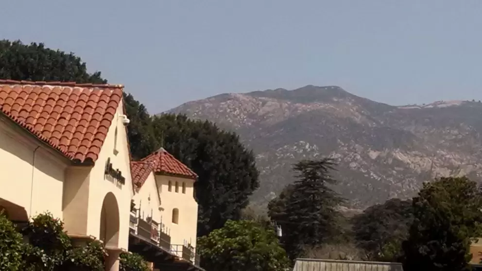 View of high mountains, cute tower, and red-tiled rooftops.