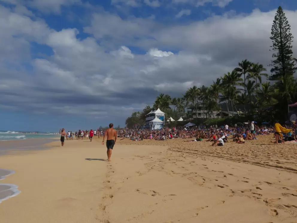 A young man walks along the shore at the Pipeline Masters.