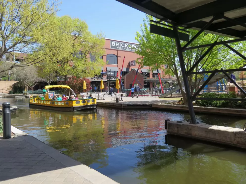 A yellow boat takes tourists for a ride down the canal.