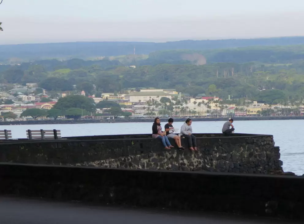 Young people sitting on a rock wall at the bay.