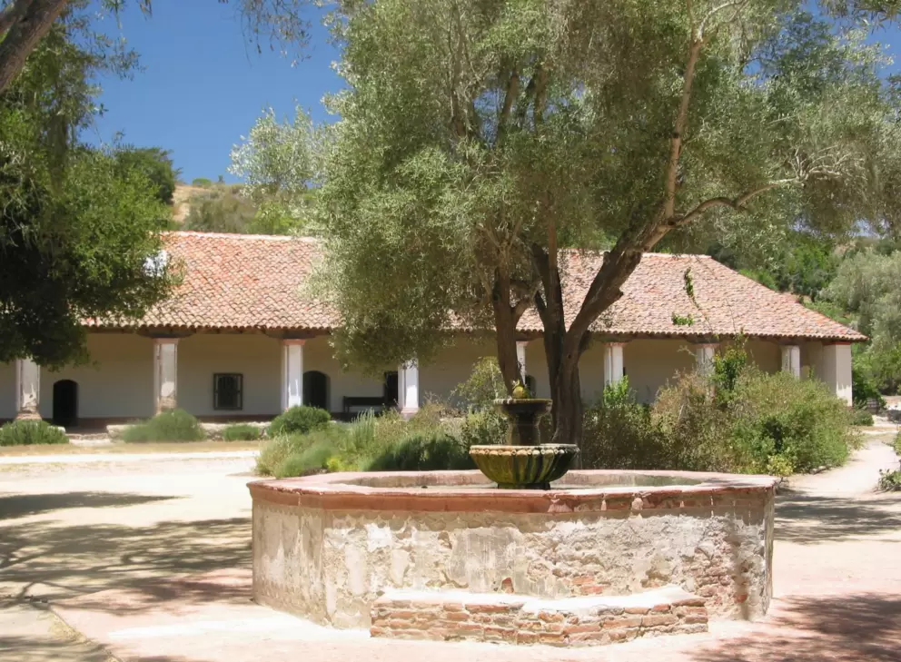 Fountain in the garden with the mission's many rooms behind.