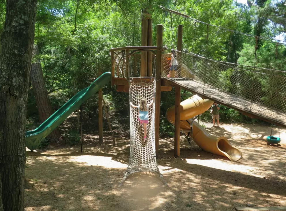 Playground with rope climbey, swinging bridge, and twisty slide.