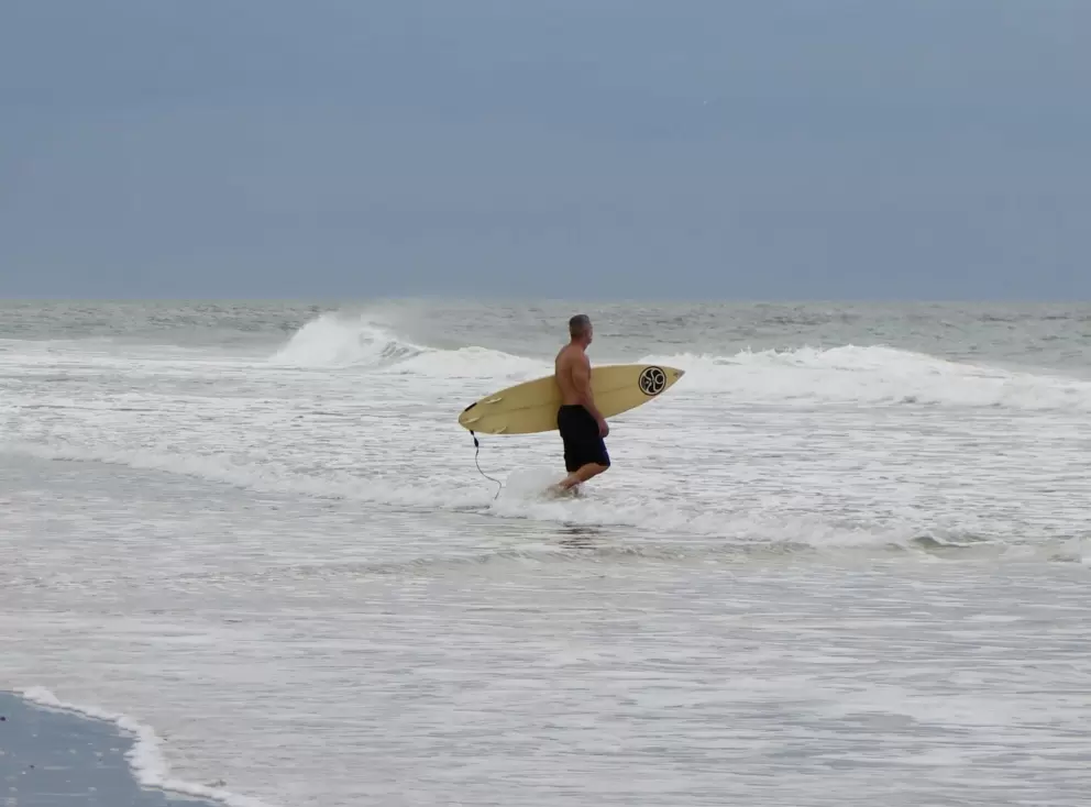A surfer heads out.
