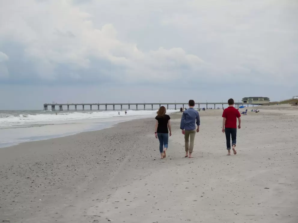 Three young people walk toward the pier.