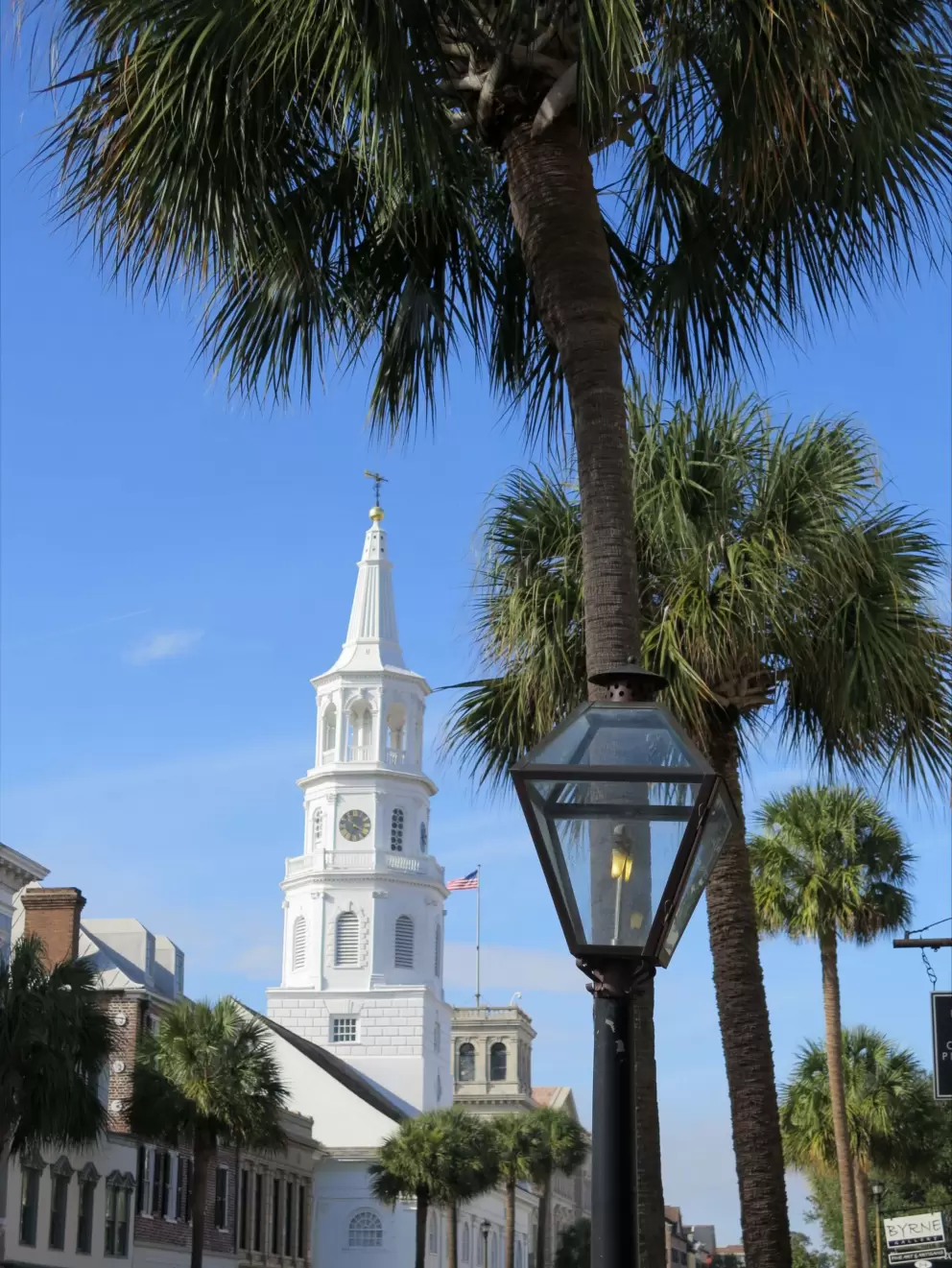 Church steeple, lamppost, and palm trees.