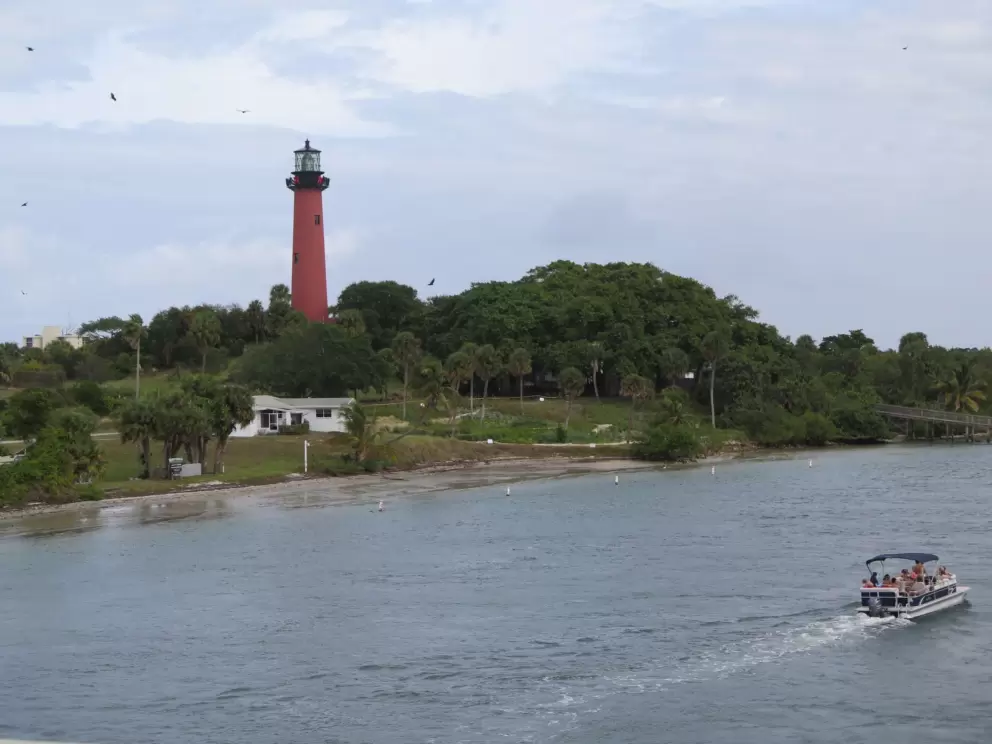 A boat zips by the beautiful Jupiter lighthouse.