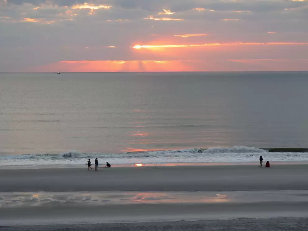 Beachgoers stop to admire the sunrise.