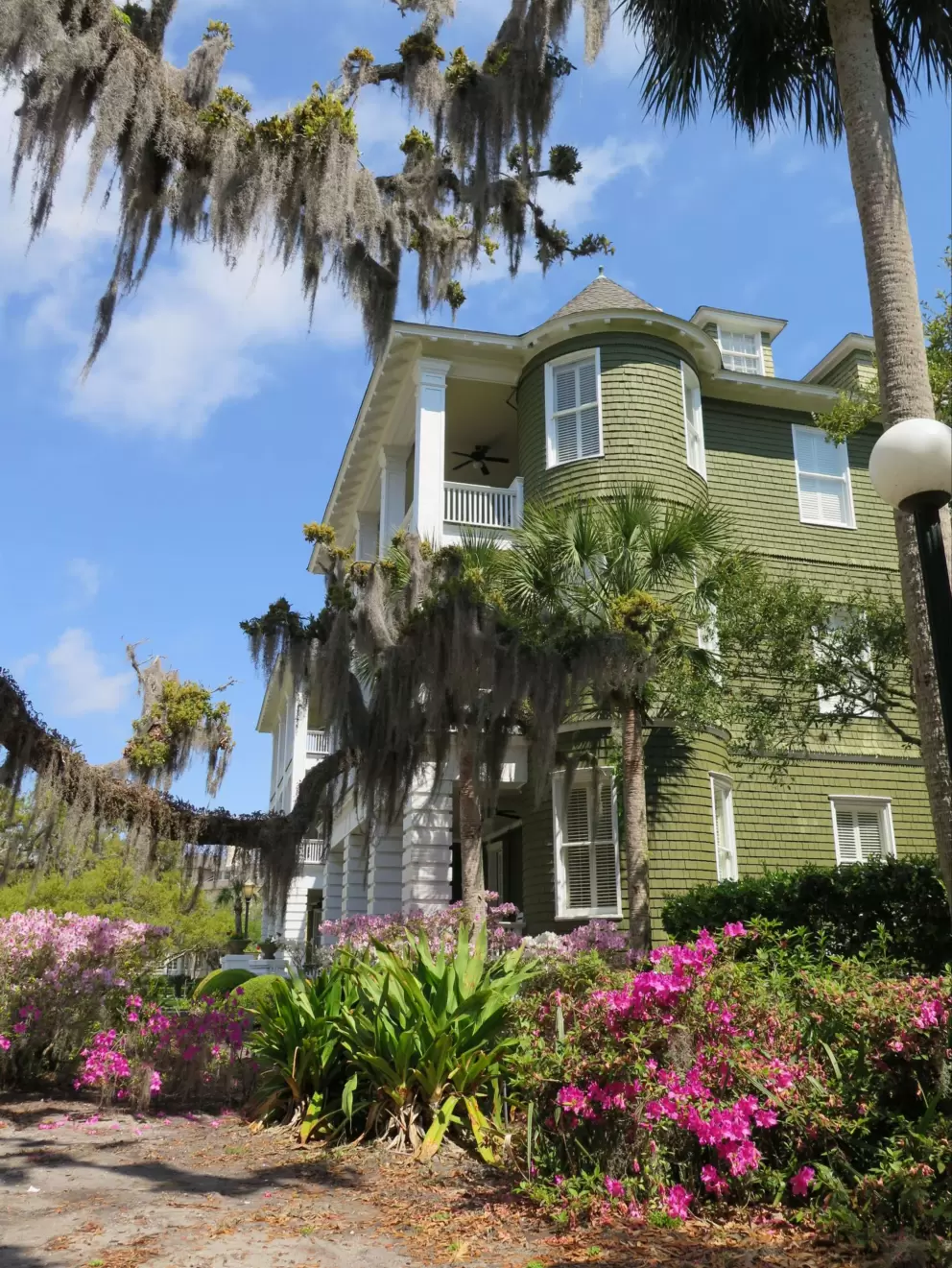 A pretty cottage with azalea flowers outside.