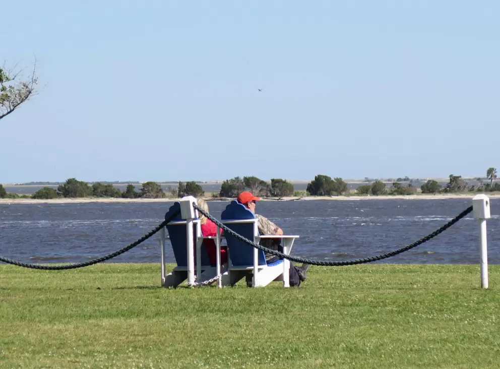 A couple watches the river from the adirondack chairs.