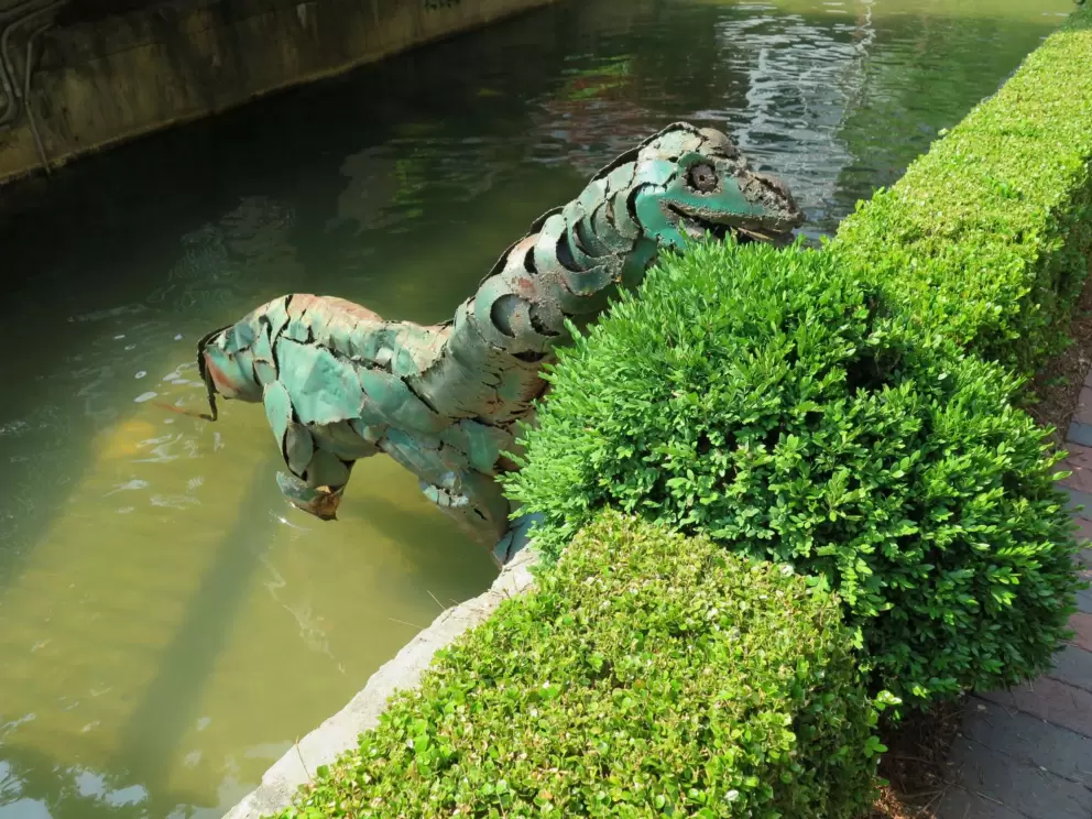 Dinosaur peeking over the bushes.