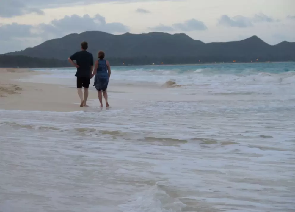 A couple enjoys a long walk down the beach.
