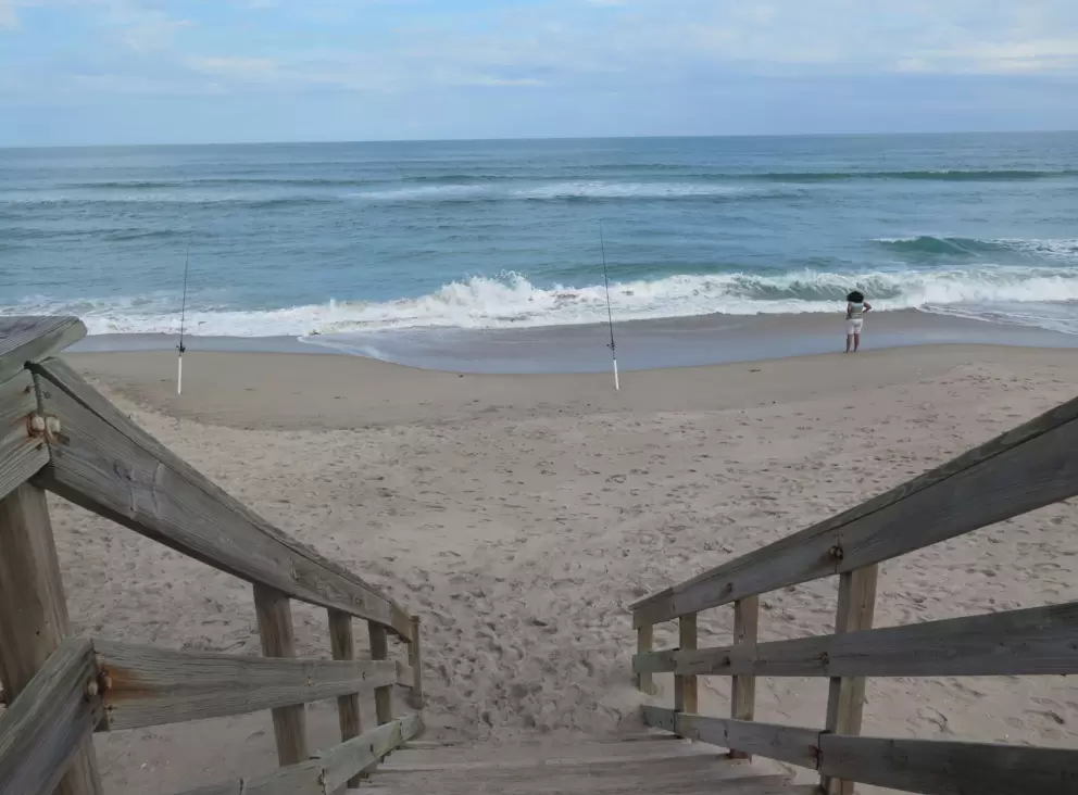 Stairs down to the beach, and fishing lines at the shore.
