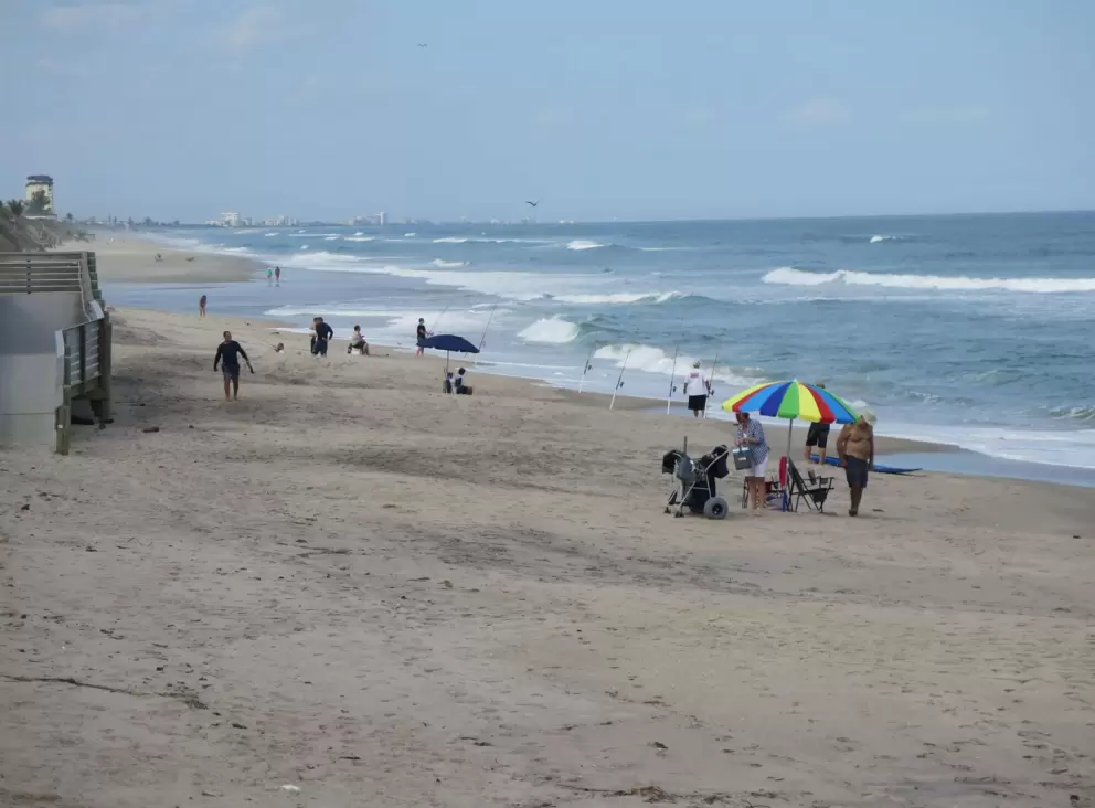 Colorful beach umbrella and lots of people enjoying the beach on a Saturday.