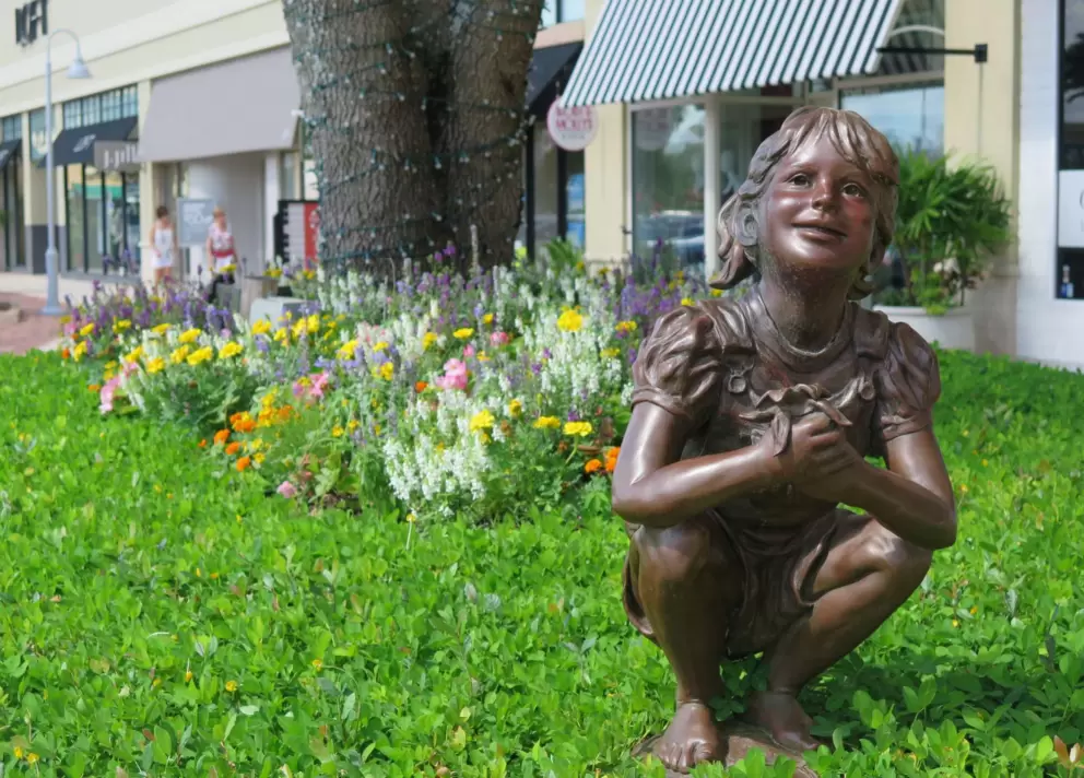 Statue of a little girl in the grass.