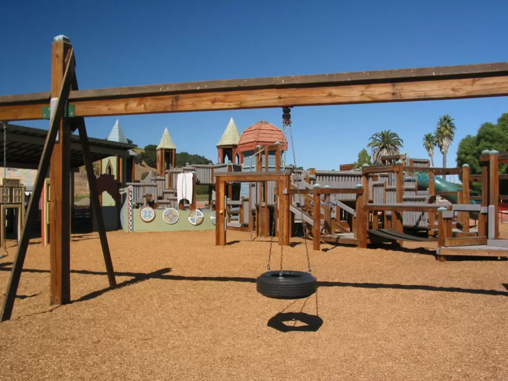 Tire swing with wooden castle in the background.