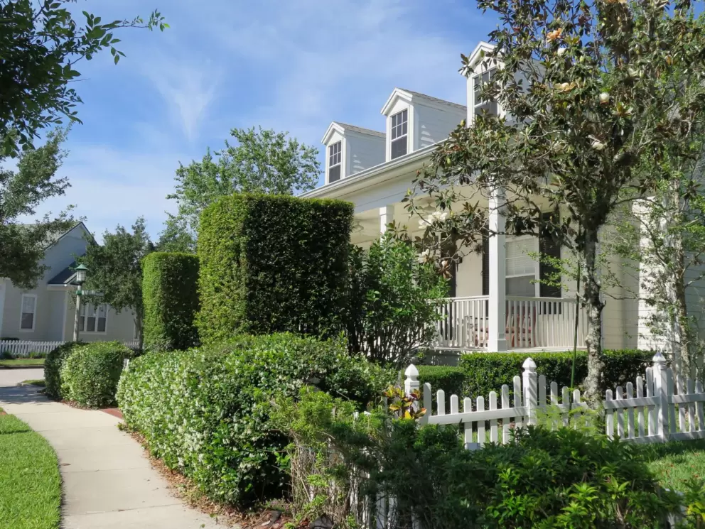 Hedges and white picket fence, around a Colonial house.
