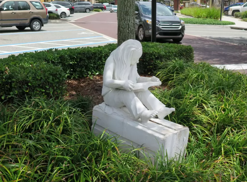 Sculpture of a girl reading under a tree.