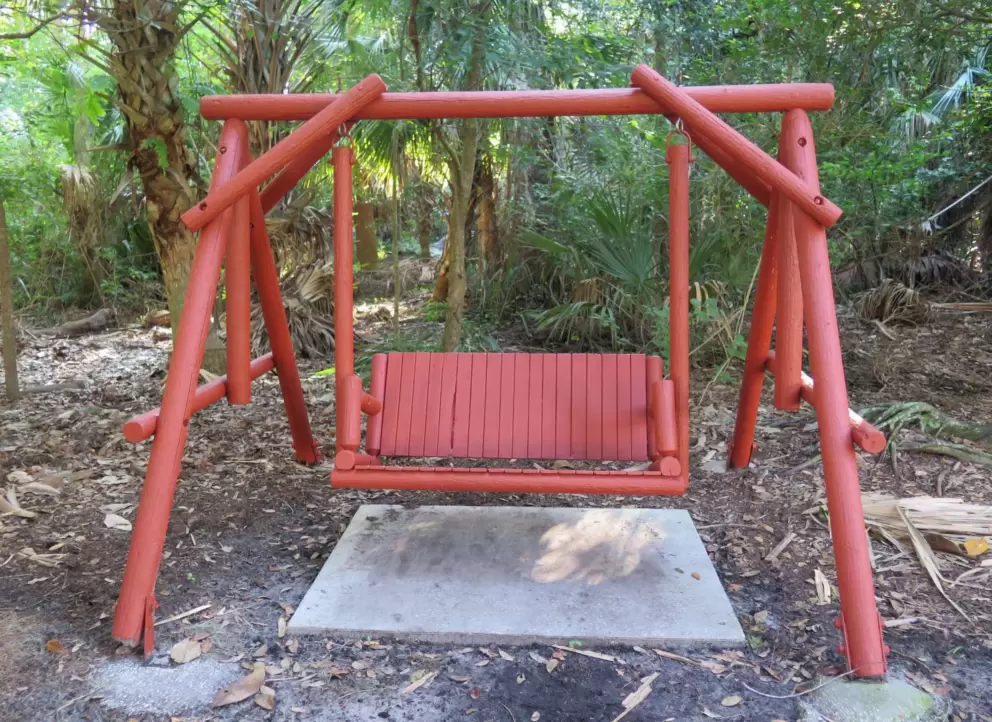Red wooden swinging bench in Central Park on Banks Rose Street.