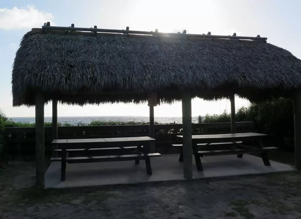 Grass shack picnic pavilion with two tables. There are six of these pavilions, all with ocean views.
