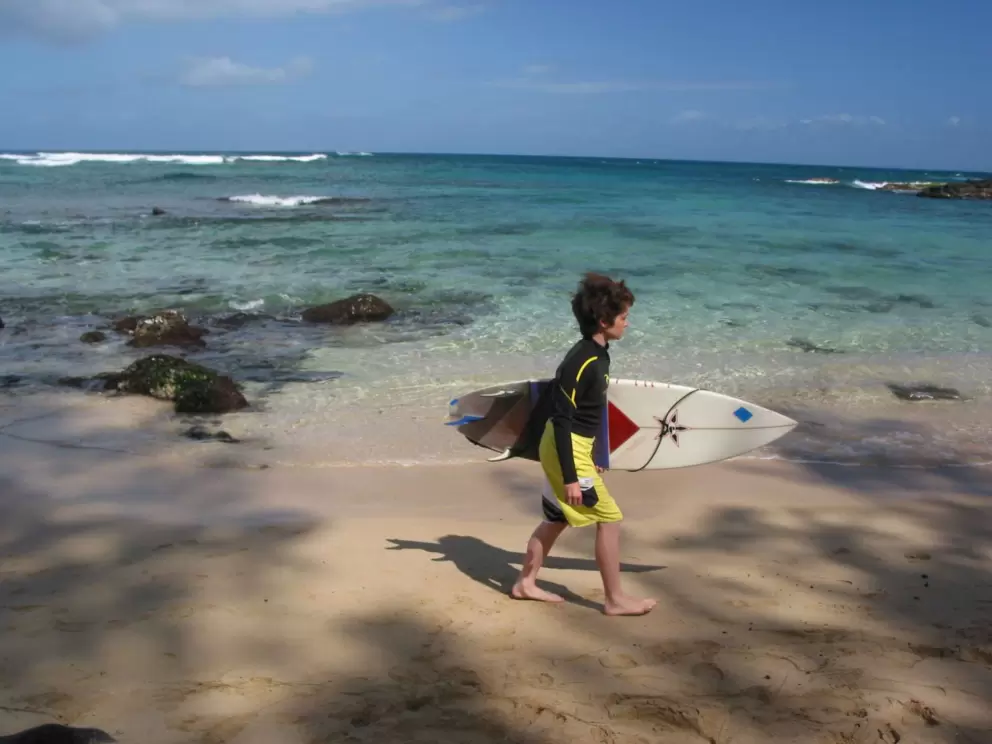 A young surfer arrives to check out the waves. Laniakea Beach was just a surfing beach before the turtles made it their home.