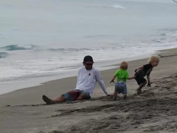 A dad plays with his kids at the shore.