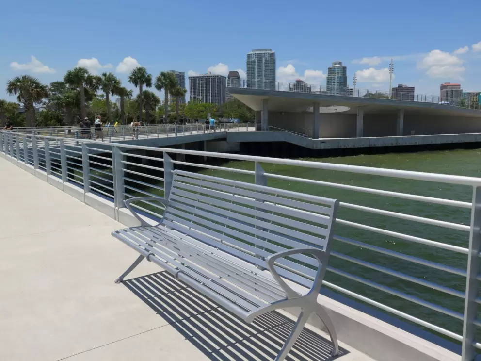 Metal bench and railing, with pretty sky and water behind.