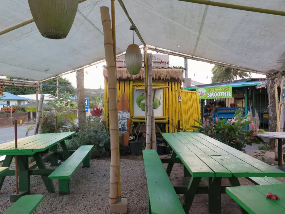 Green picnic tables outside a Thai food truck.