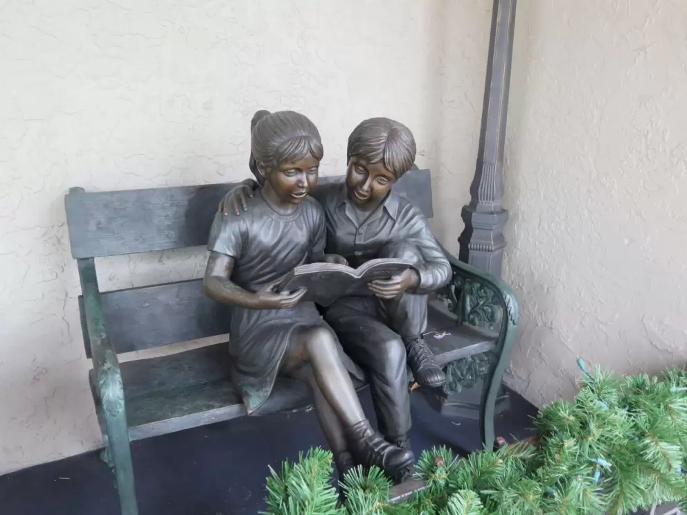 Statue of children reading on a bench.