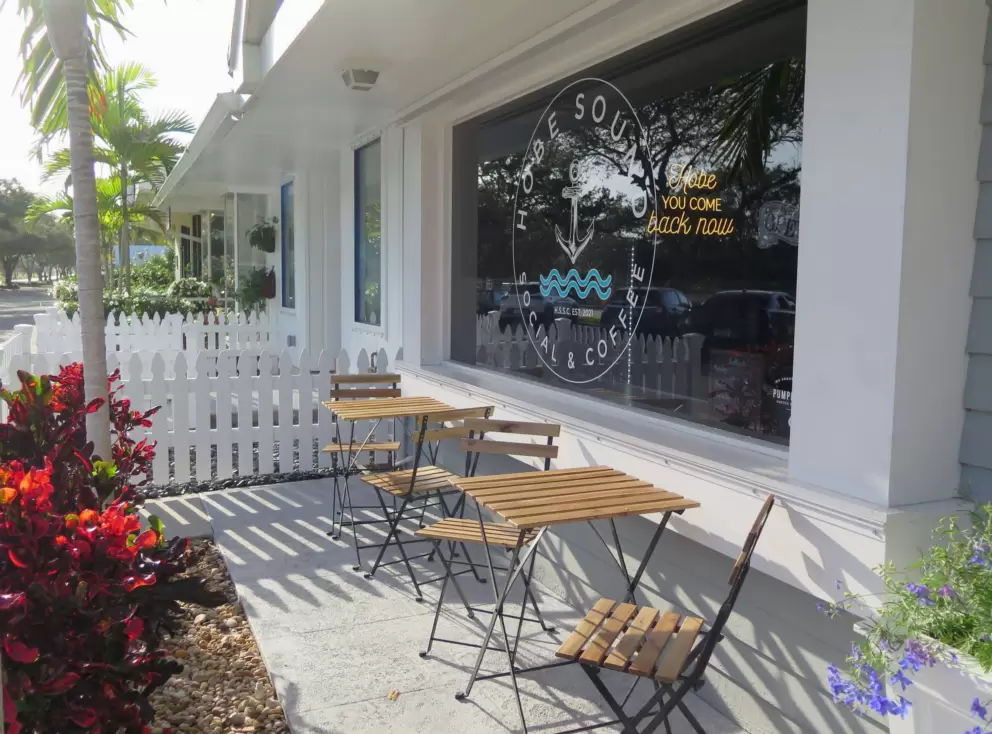 Sunny tables and flower basket, at Hobe Sound Social and Coffee.