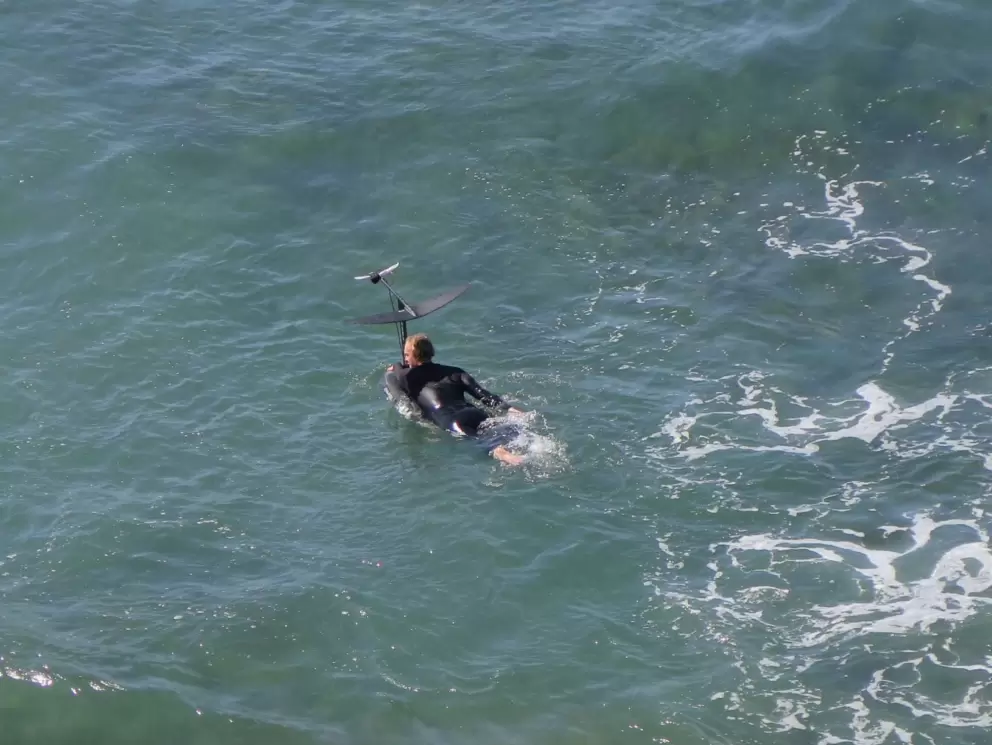 A surfer with a hydrofoil board heads out. 