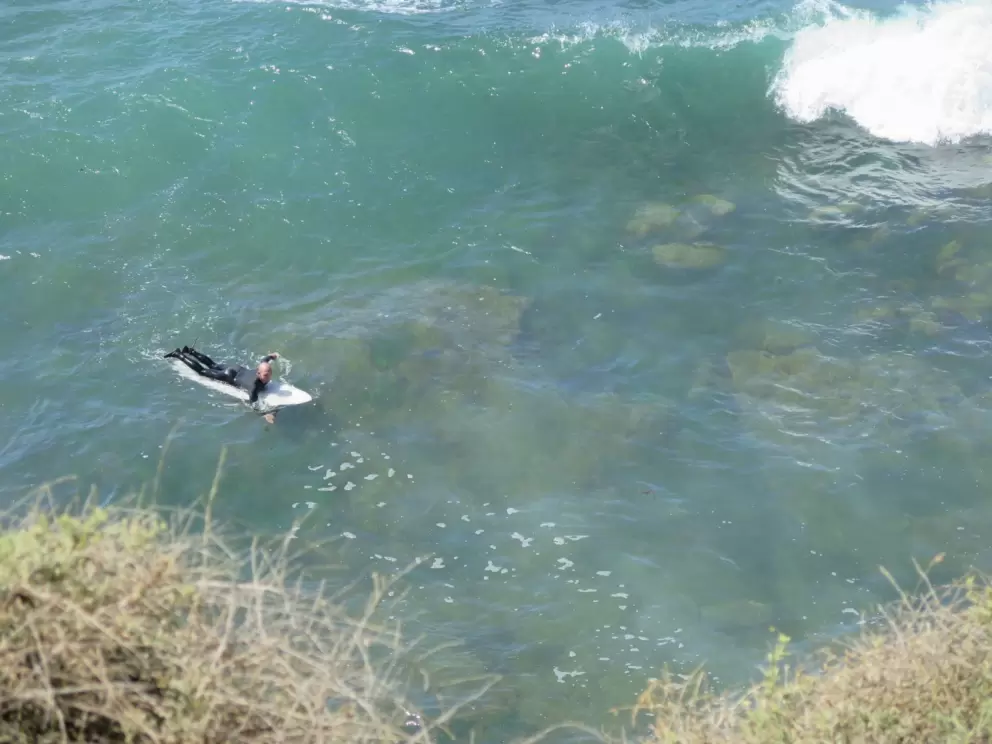 A surfer floats over the crystal clear water.