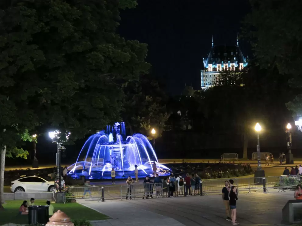 People stand in the grounds of the Parliament Building at night.