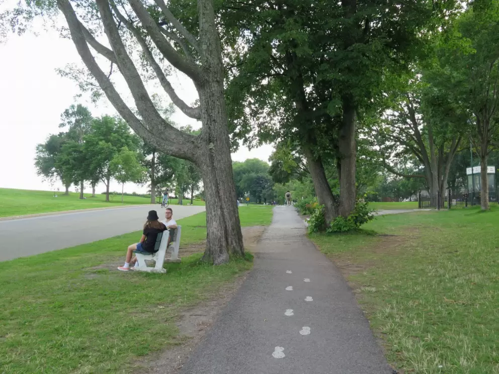 A couple sits on a bench by a walking path in Plains of Abraham. 