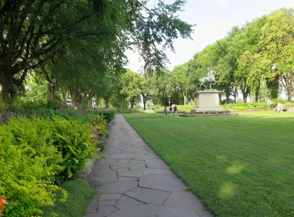 Path that goes around the edge of Joan of Arc Garden, and statue in the middle of the lawn.