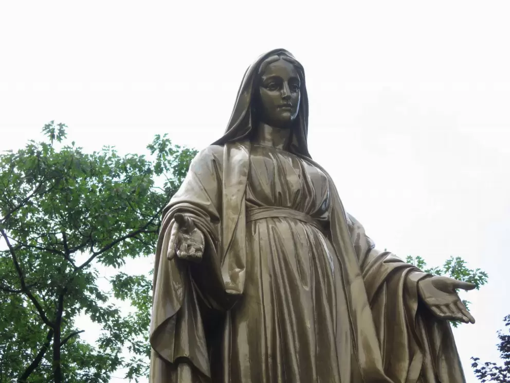 A calming statue of Mary in the garden near the fountain. 
