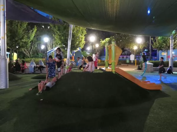 Playground with hills, under a shade canopy.