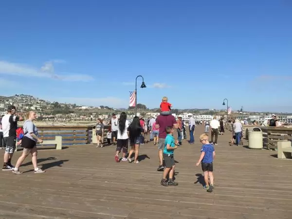 Families and friends walk along the pier. 