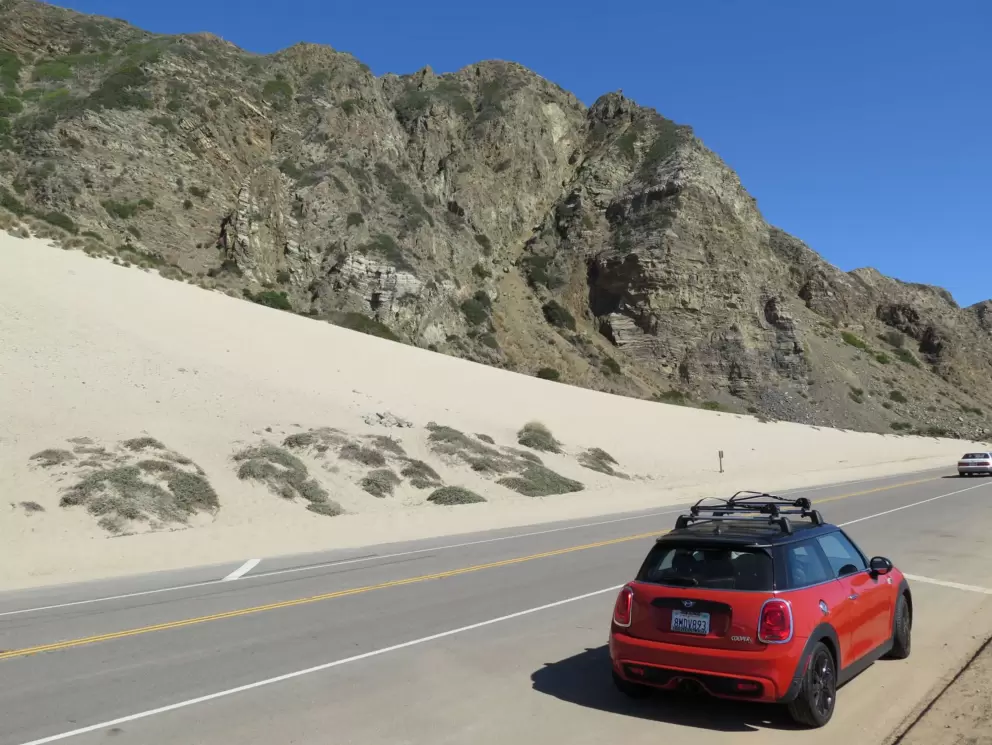 Red car by the sand dune. 
