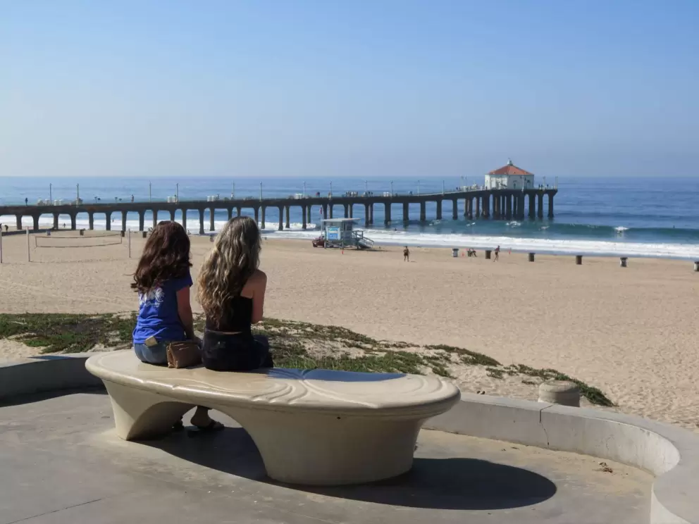 Girls sitting on a bench, looking out at the pier. 