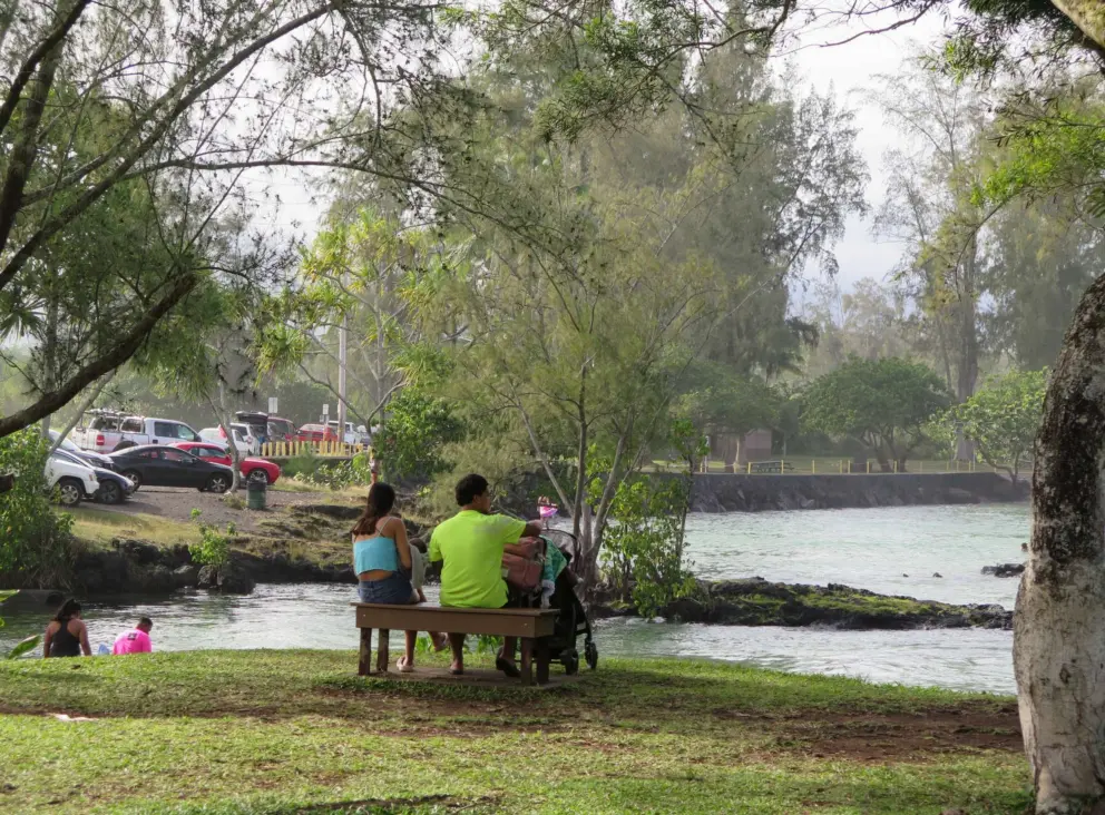 Family sitting on a bench by the spring. 