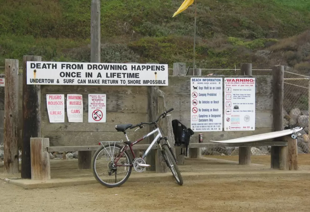 Sign warning of the dangers of surfing or swimming here. 