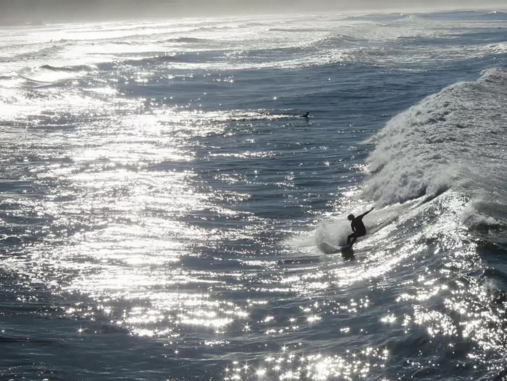 A surfer in the glistening water at the SLO Cal Surf Contest. 