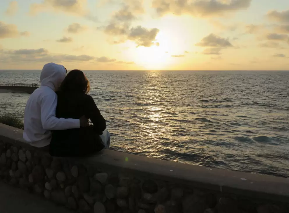 A couple watches the sunset. 