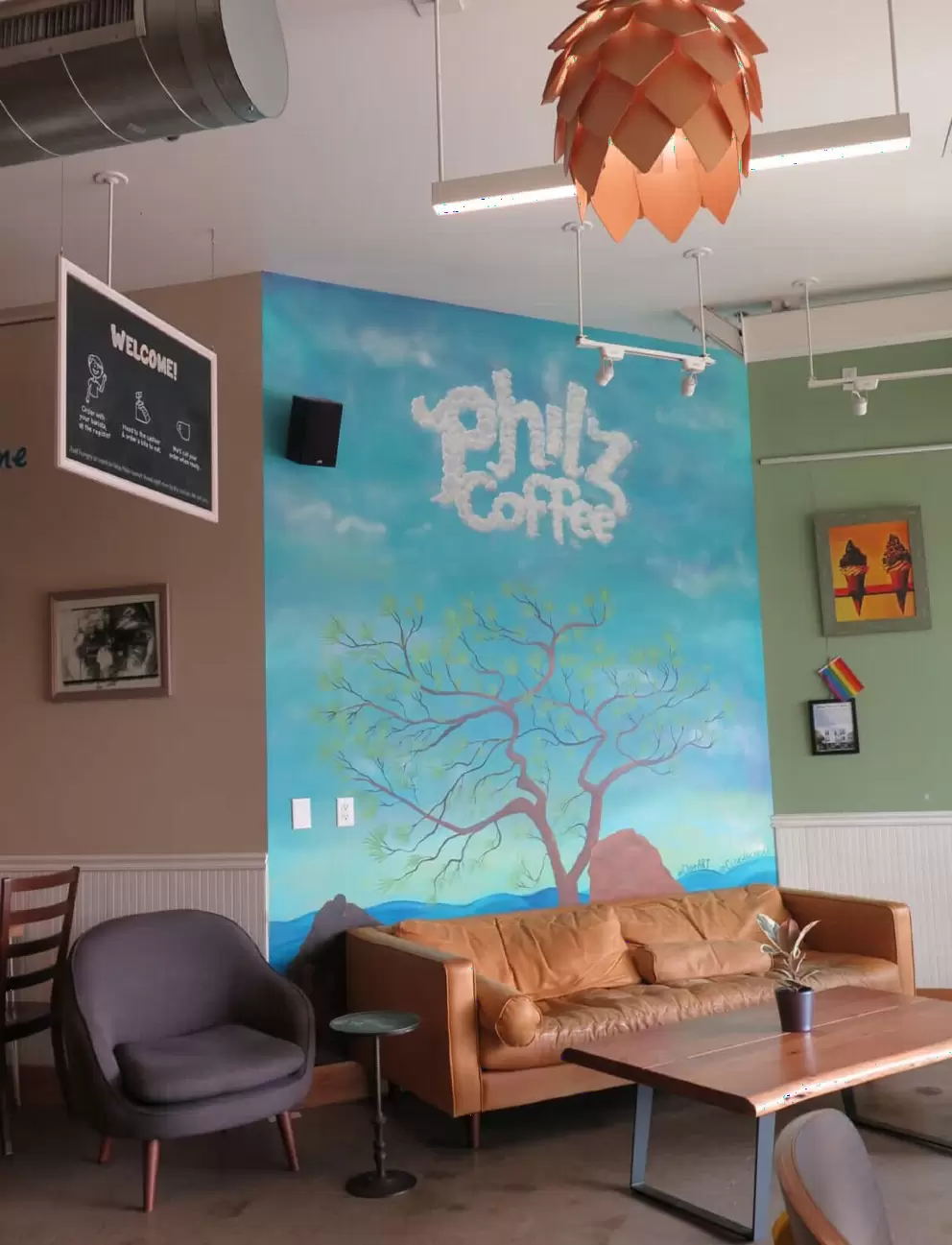 The mural and golden chandelier inside Philz Coffee. 