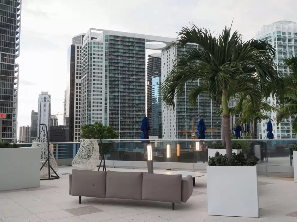 Couch and view of building with circle atop, at the Kimpton Epic rooftop bar area. 