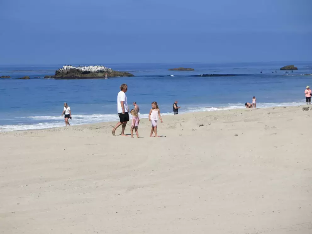 A family walks on the white sand. 