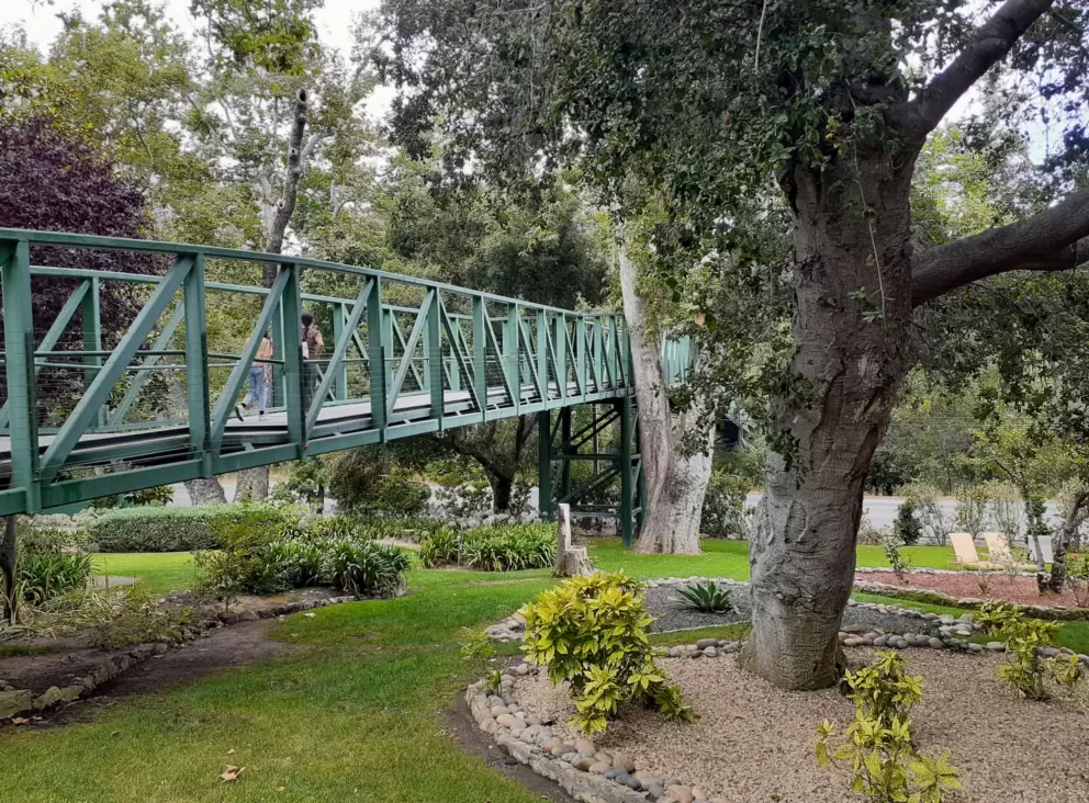The green pedestrian bridge goes over the garden at Sycamore Mineral Springs Resort. 