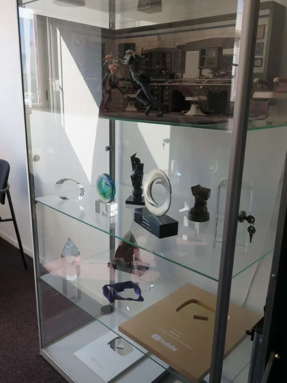 Awards and items on display in a glass case at Blender Foundation. 