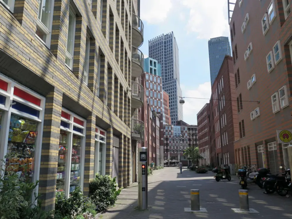Yellow stripey brick building and views of skyscrapers in the distance, near Muzenplein. 